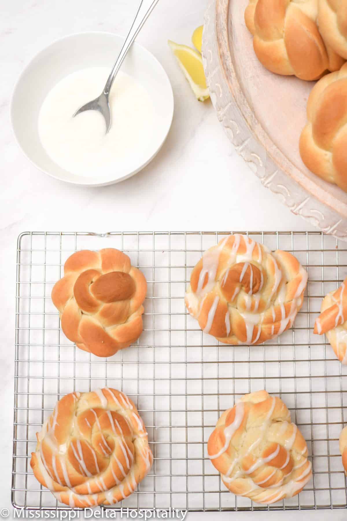 Lemon knots on a cooling rack with three of them iced and one not. 