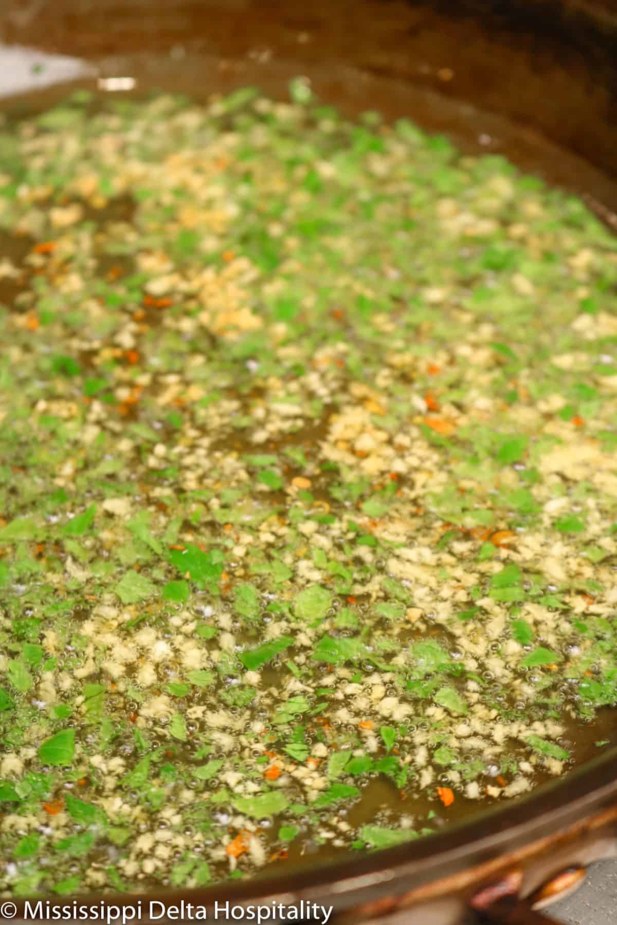 garlic, red pepper flakes, and parsley in a pan being cooked in oil