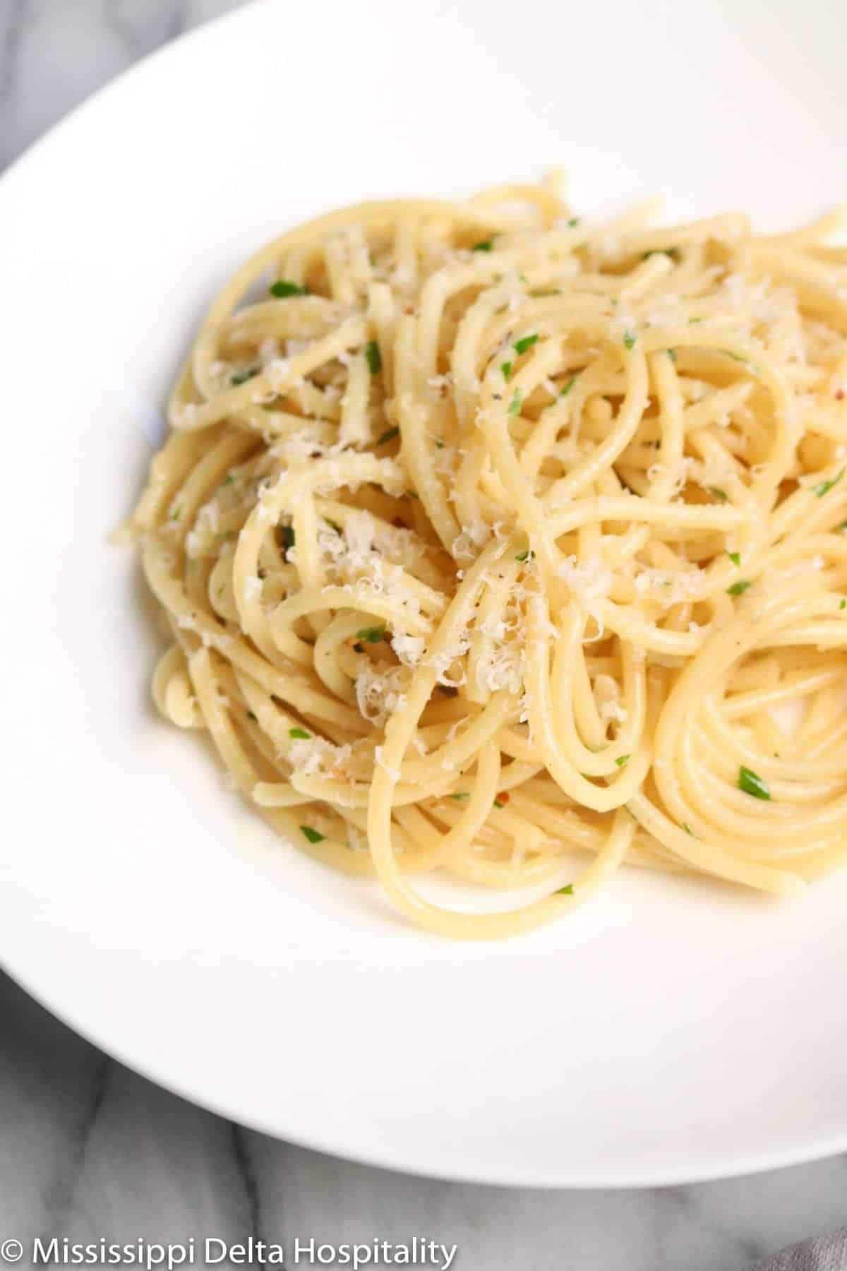 a bowl with spaghetti aglio e olio on a marble board