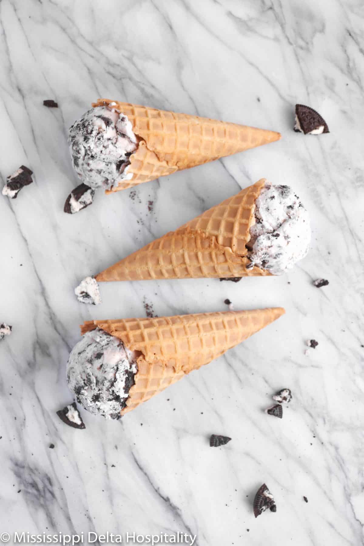 three waffle cones with cookies and cream ladying down on a marble board