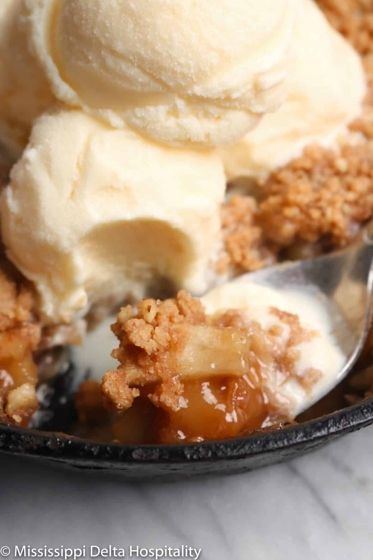 a spoonful of apple crumble in a cast iron skillet