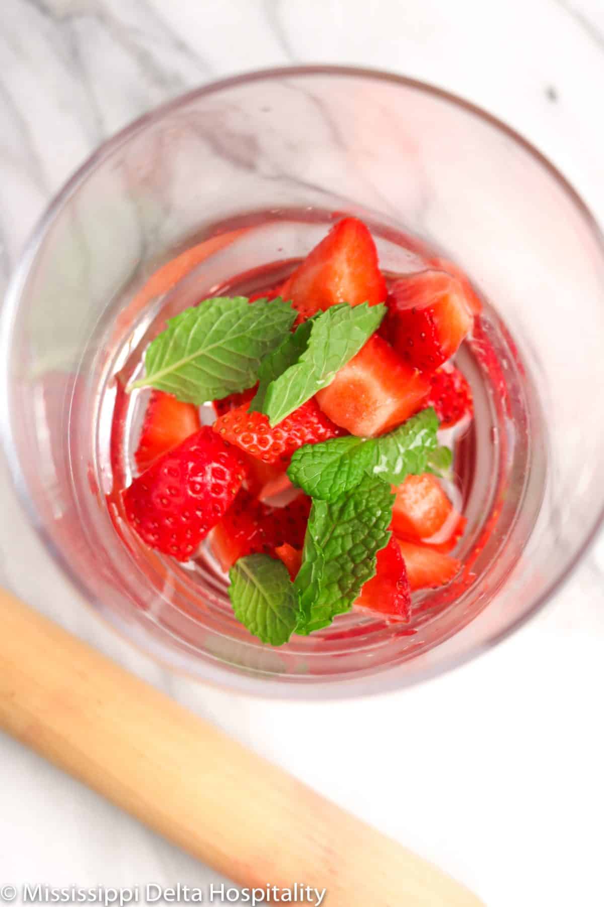 strawberries and mint and simple syrup in a glass