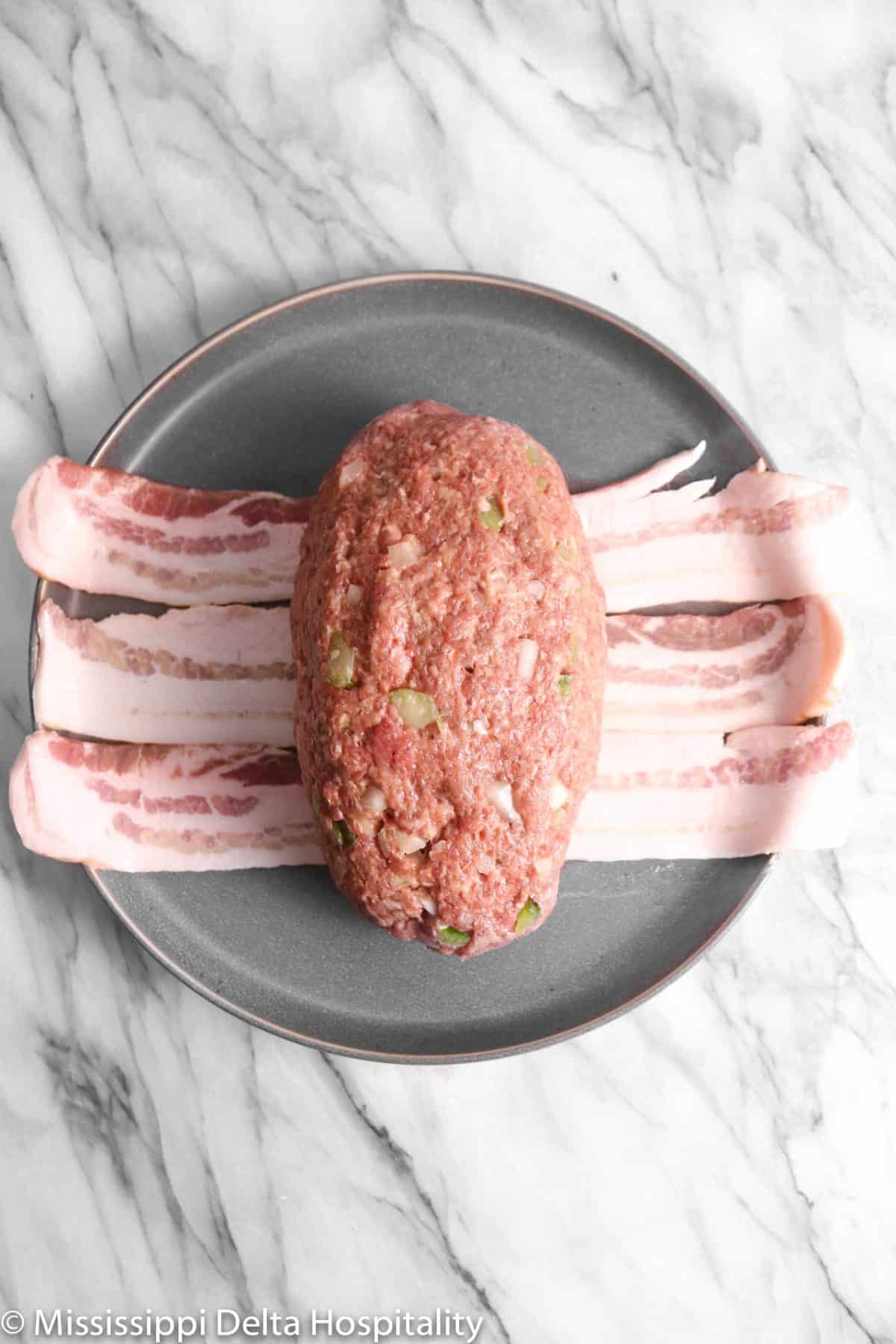 meatloaf formed and laying on three pieces of bacon