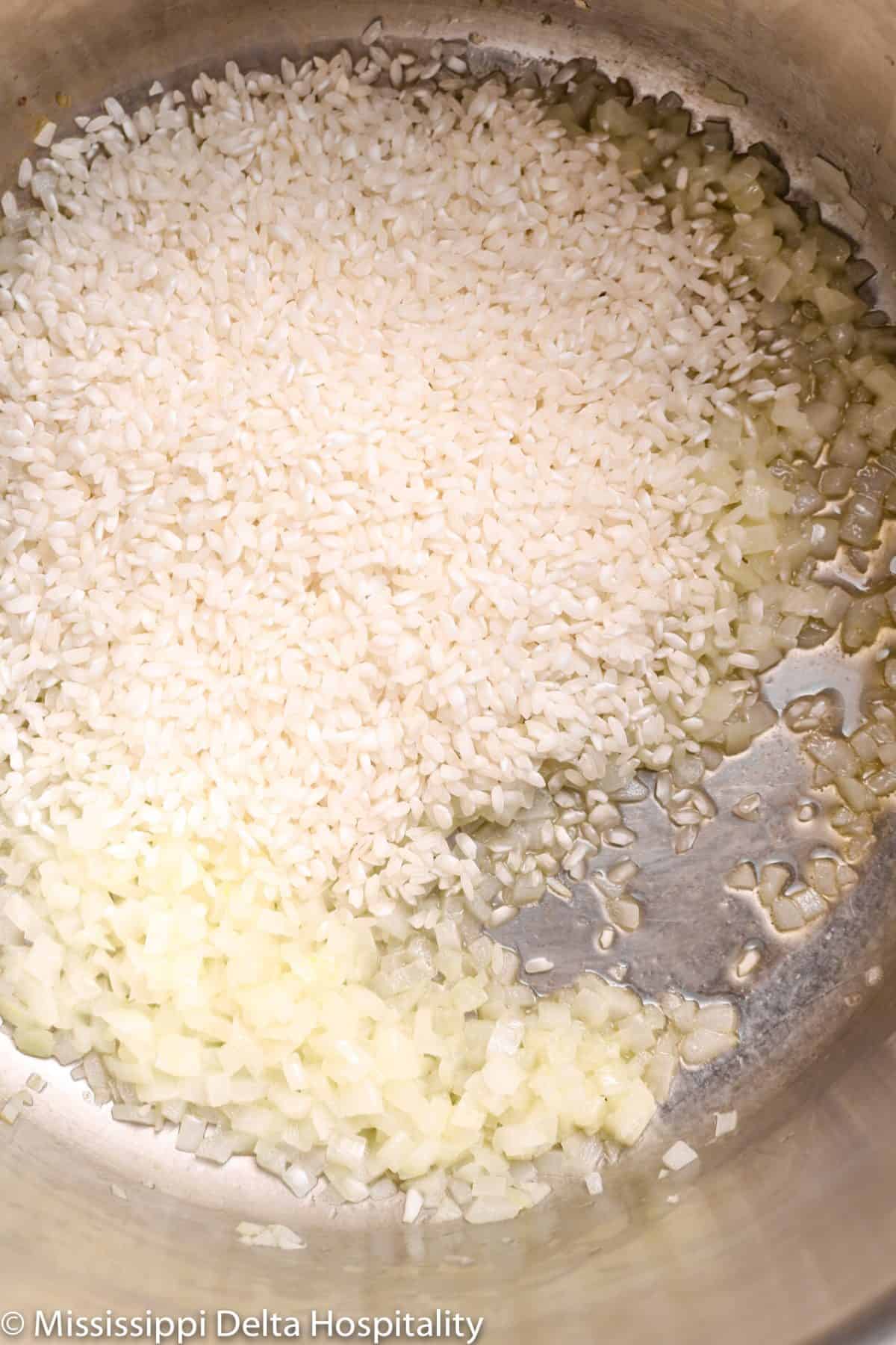 Arborio rice added to a pot with chopped onions