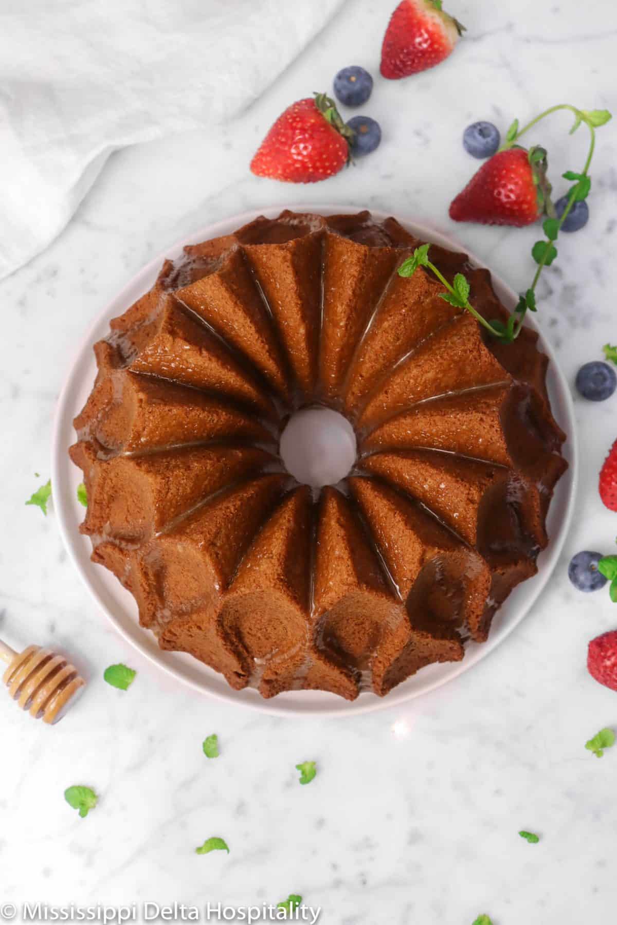 honey bundt cake with berries and mint leaves on a marble board with a white napkin