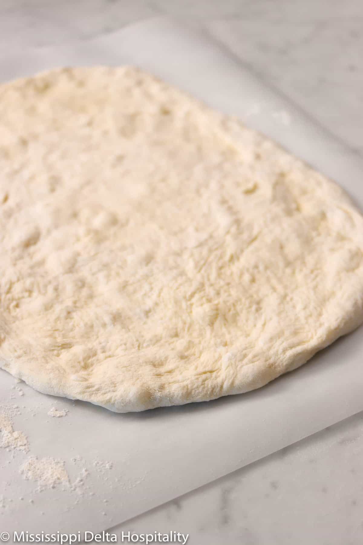 pizza dough rolled out on parchment