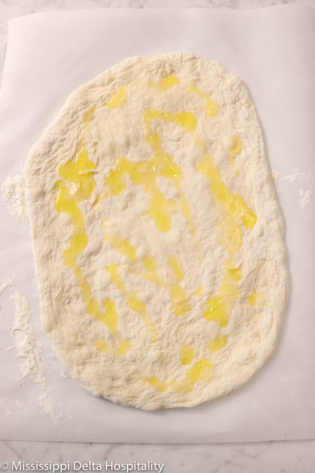 olive oil drizzled onto pizza dough