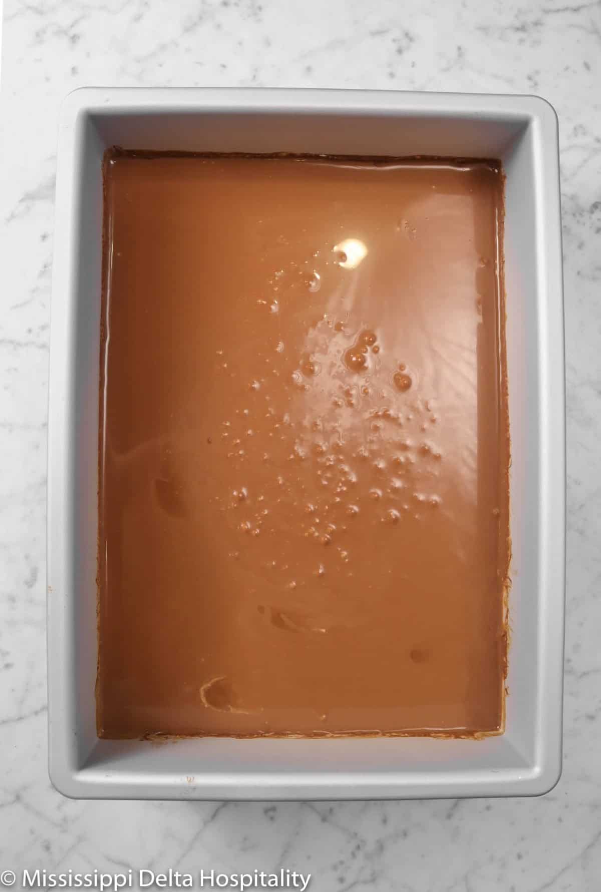 ganache in a large cake pan on a marble board