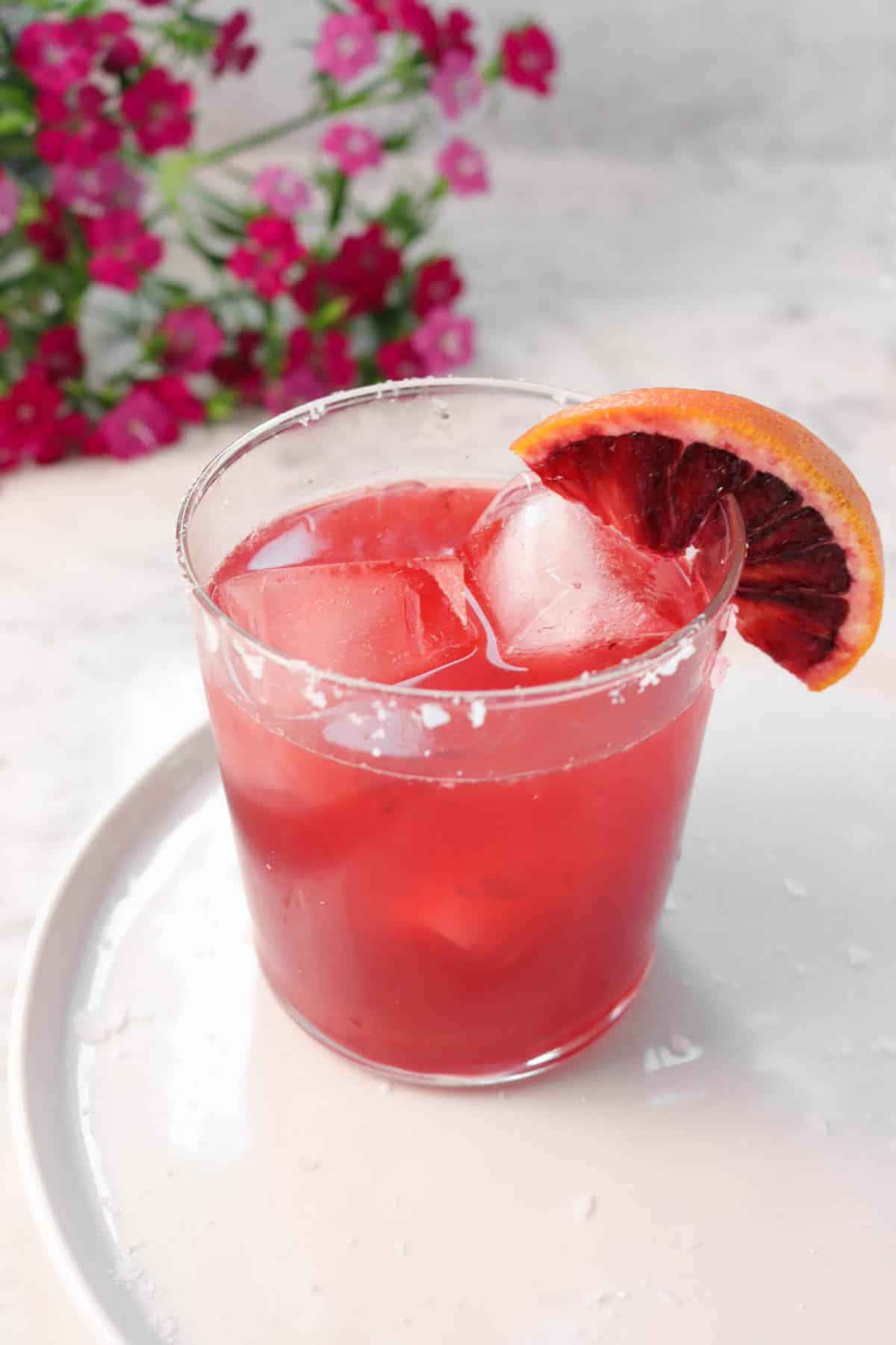 blood orange margarita on a white plate with flowers