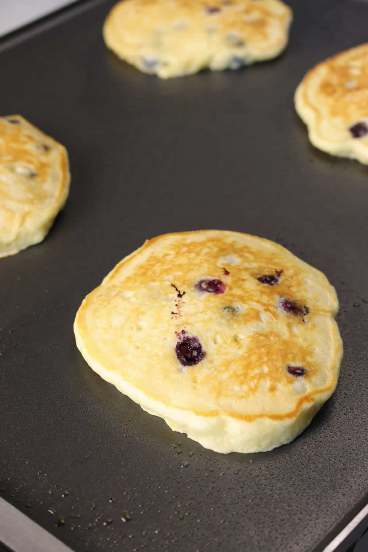 golden brown blueberry pancakes on a griddle 