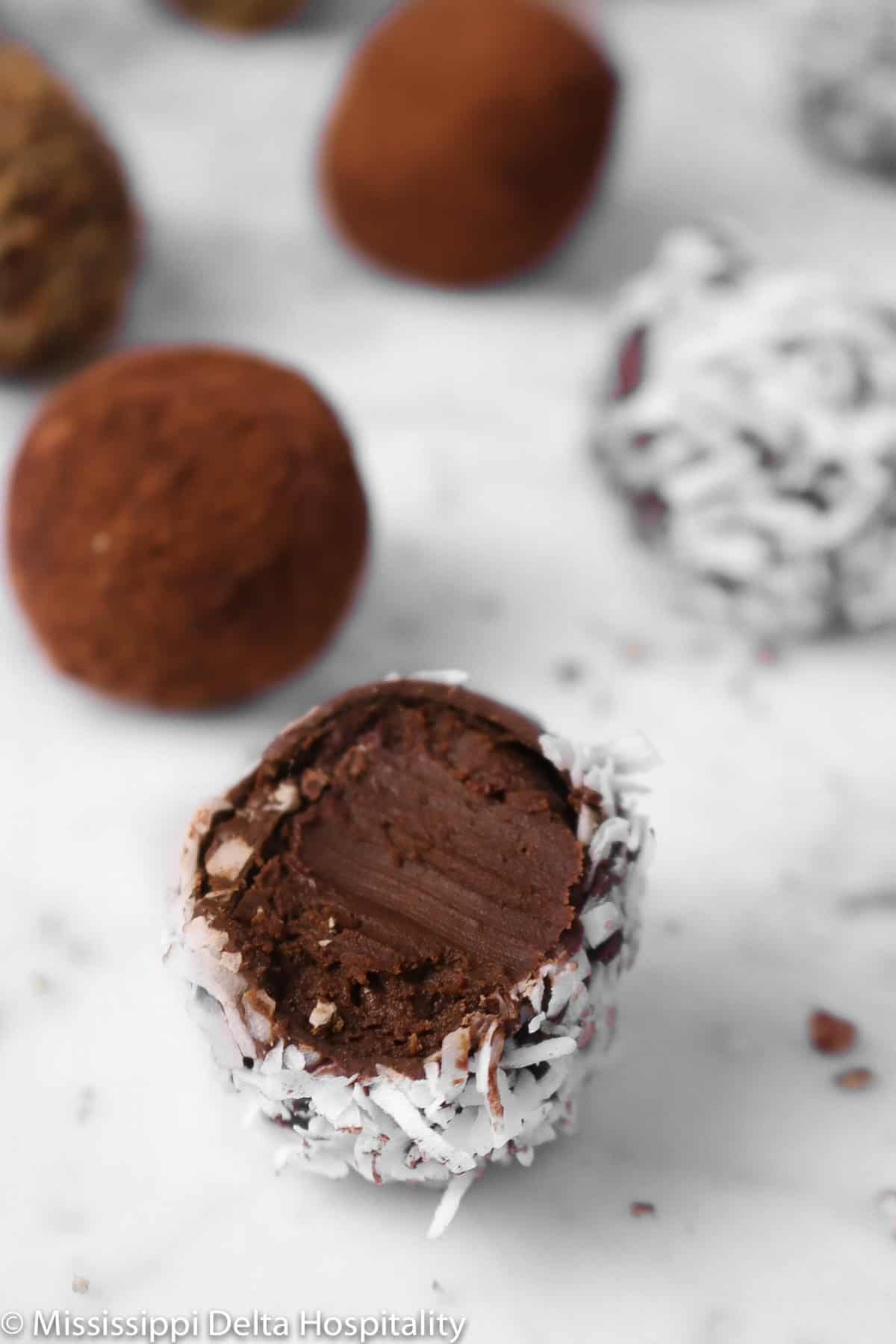 chocolate truffles on a marble table with a bite taken out of one