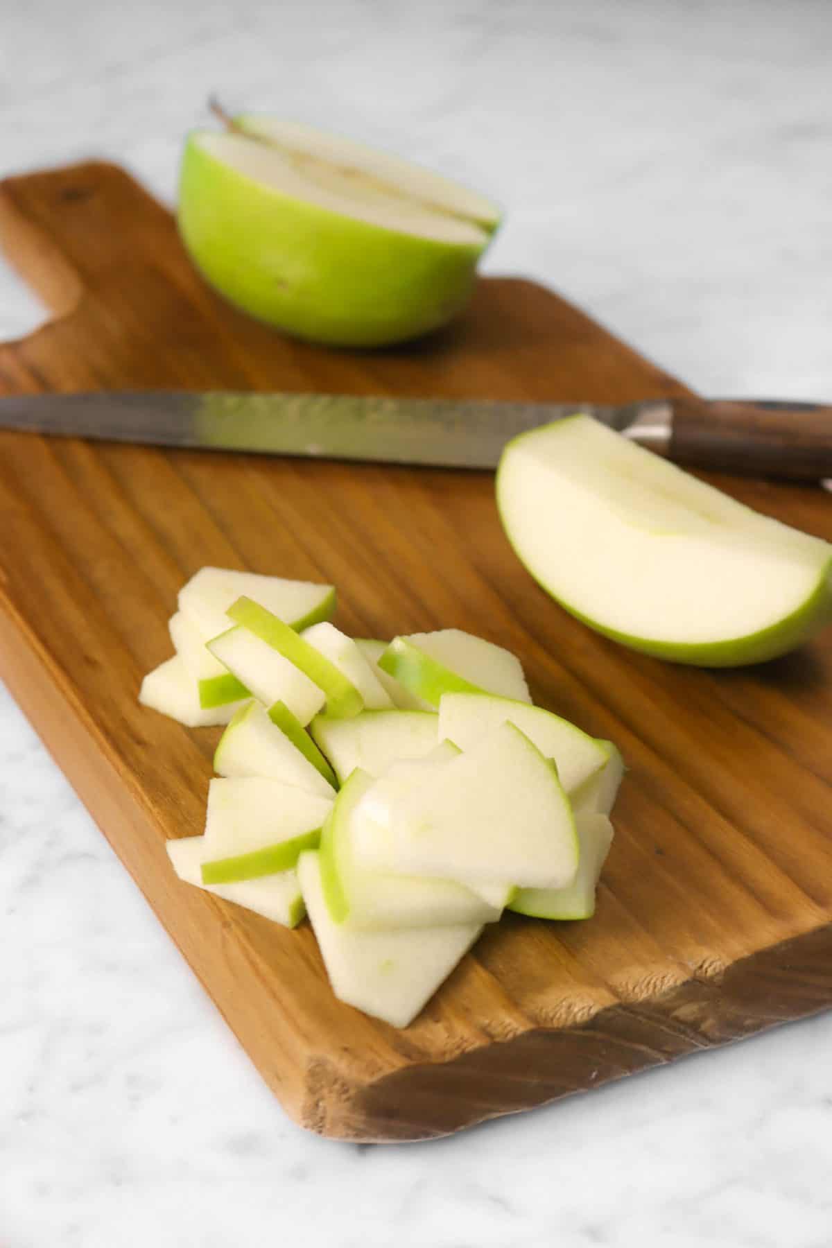green apple on a wood cutting board with a knife