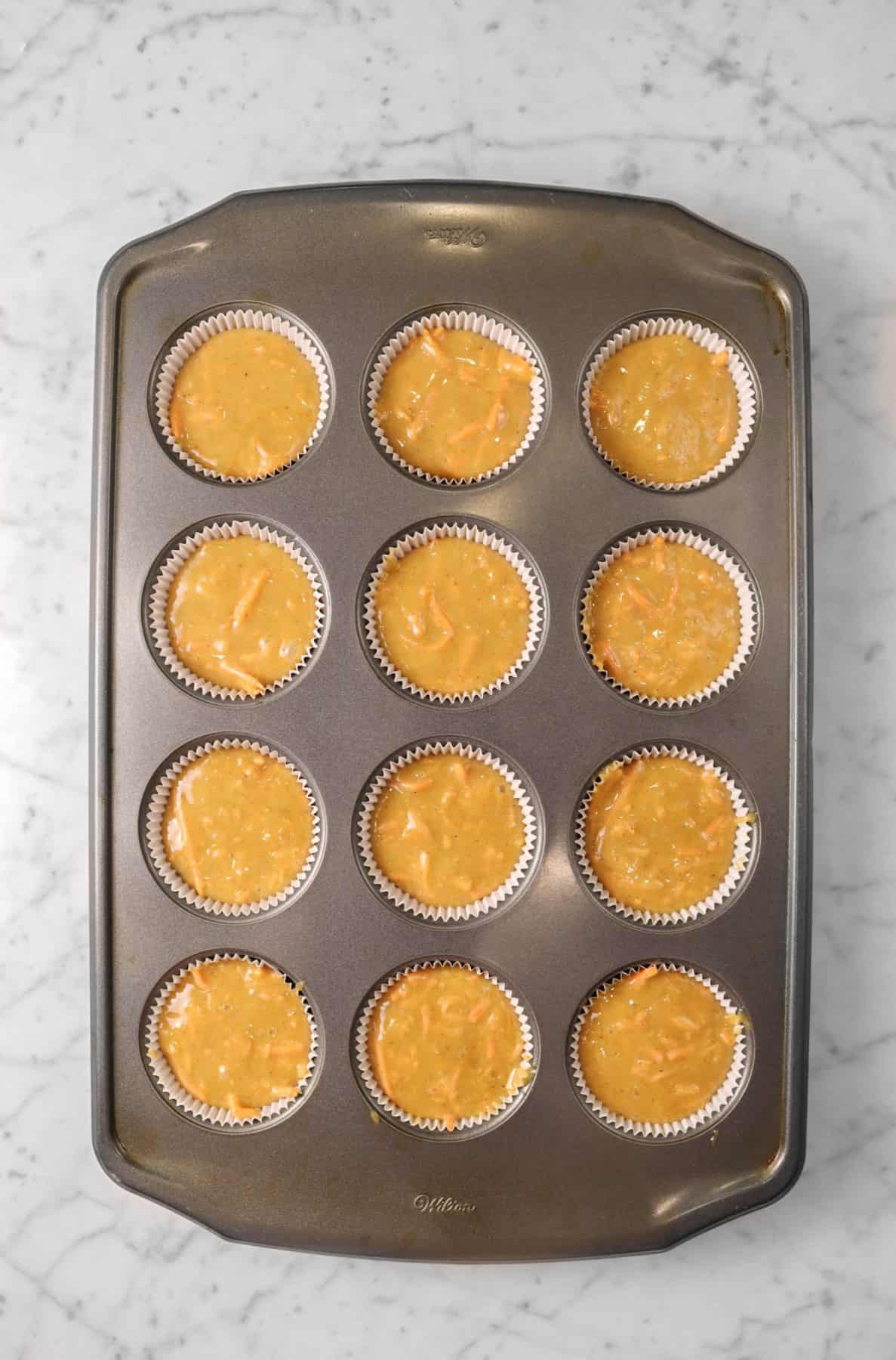 cupcake batter in a muffin tin on a marble table