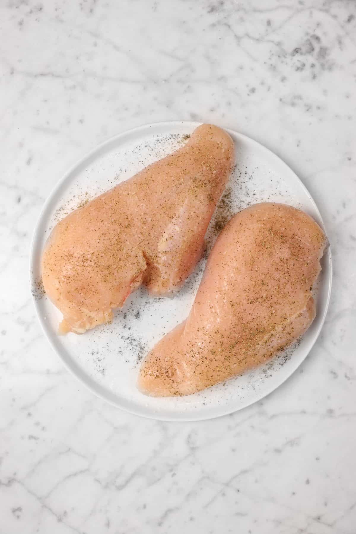 chicken breasts on a white plate with salt and pepper