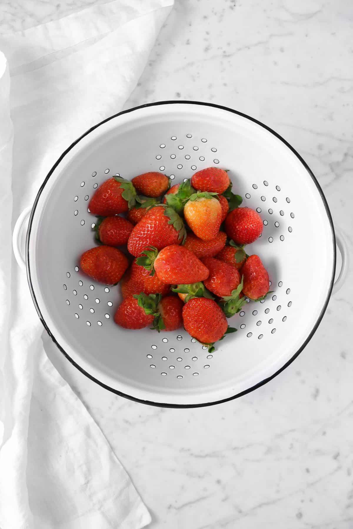strawberries in a strainer with a white napkin