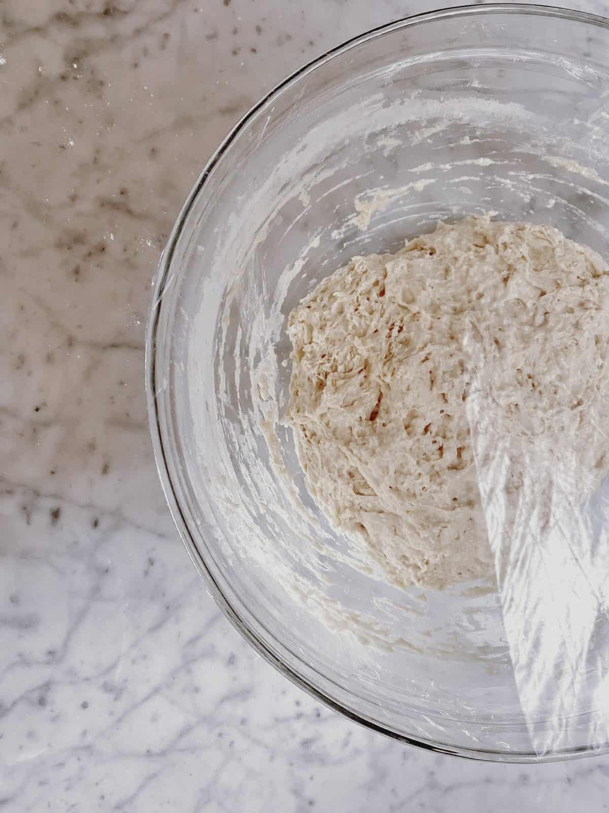 a bowl of bread dough on a marble counter