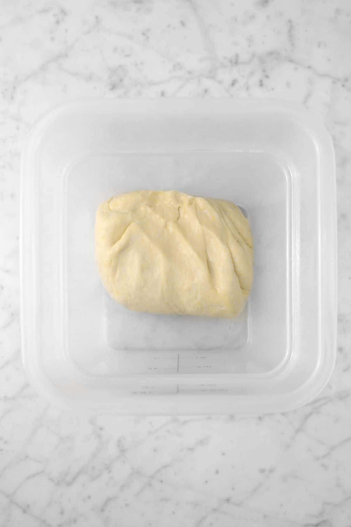 dough folded in half in a plastic container