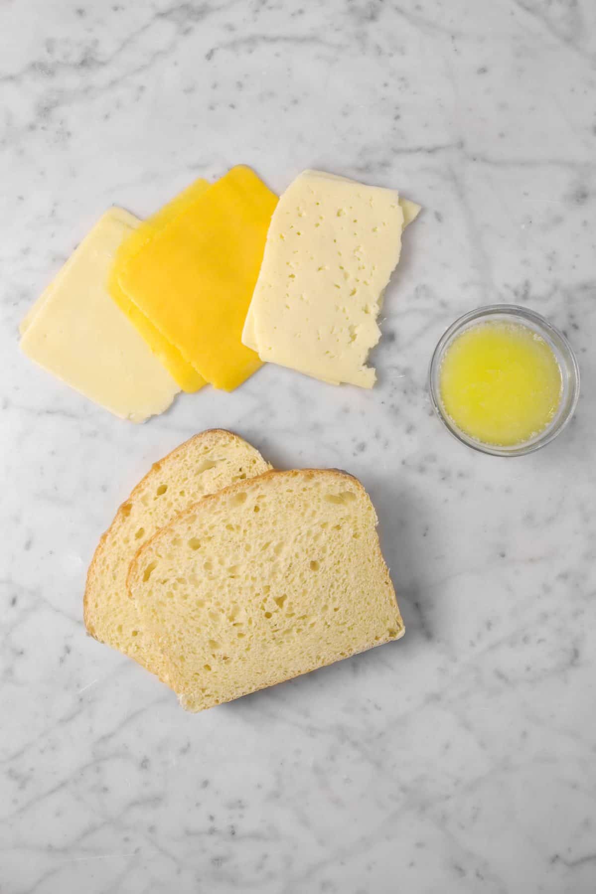 slices of cheese, bread, and melted butter on a marble counter