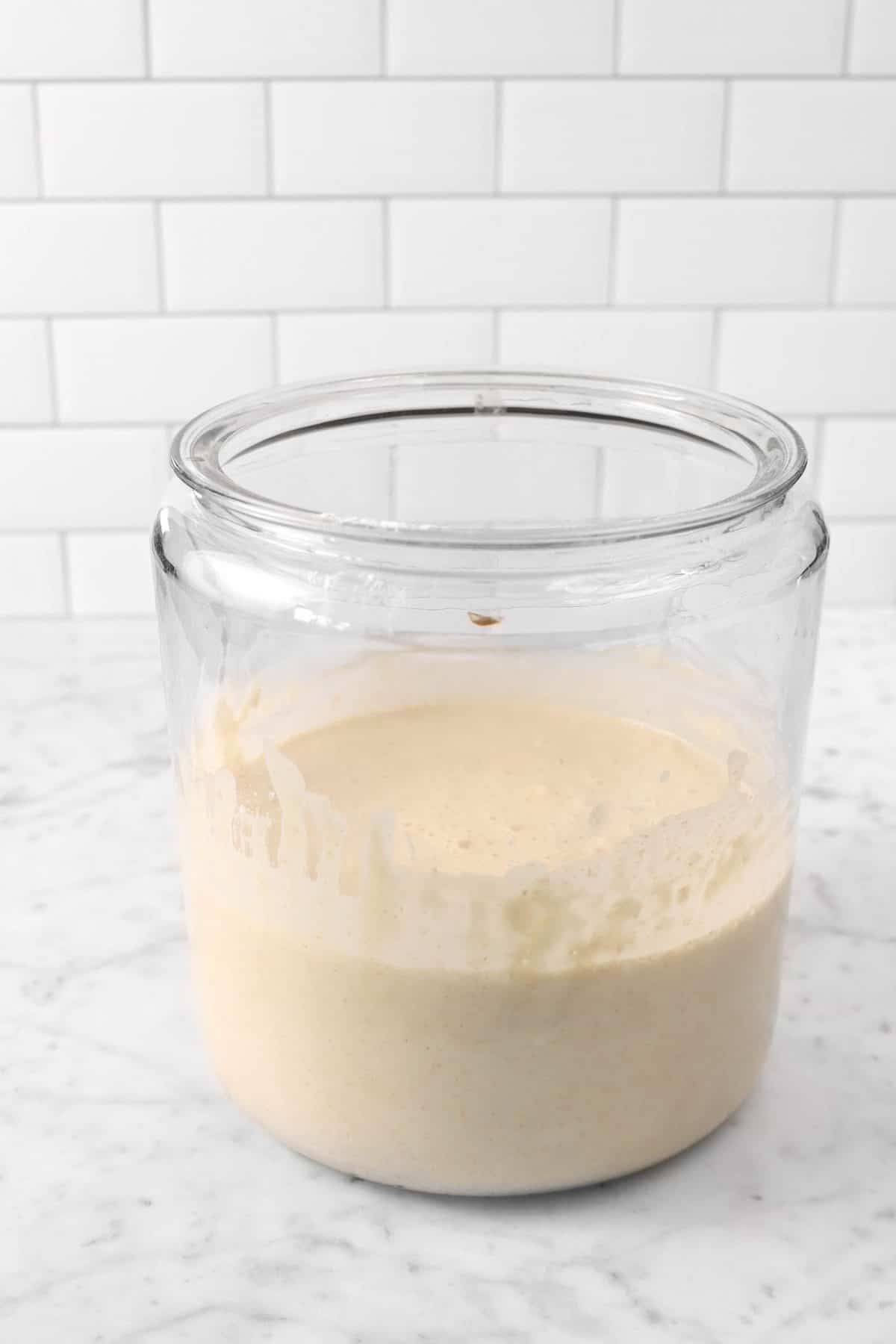 sourdough starter in a glass jar on a marble counter