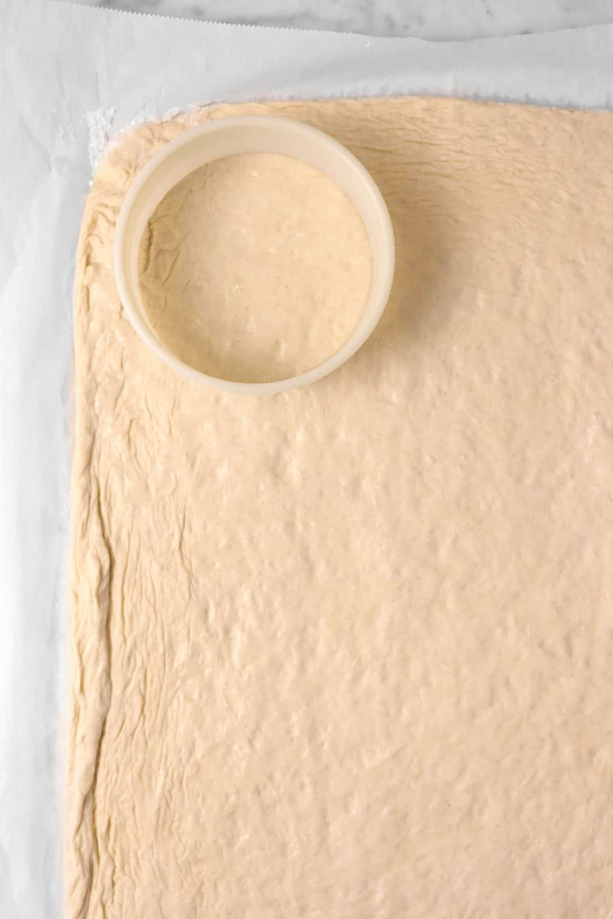 dough being cut on a piece of parchment