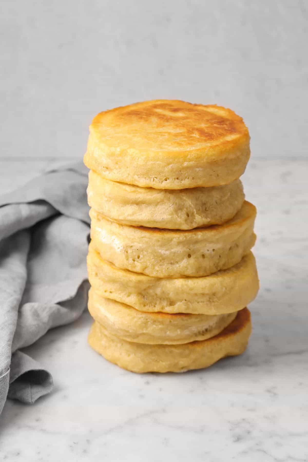 a stack of english muffins with a grey napkin on a marble counter