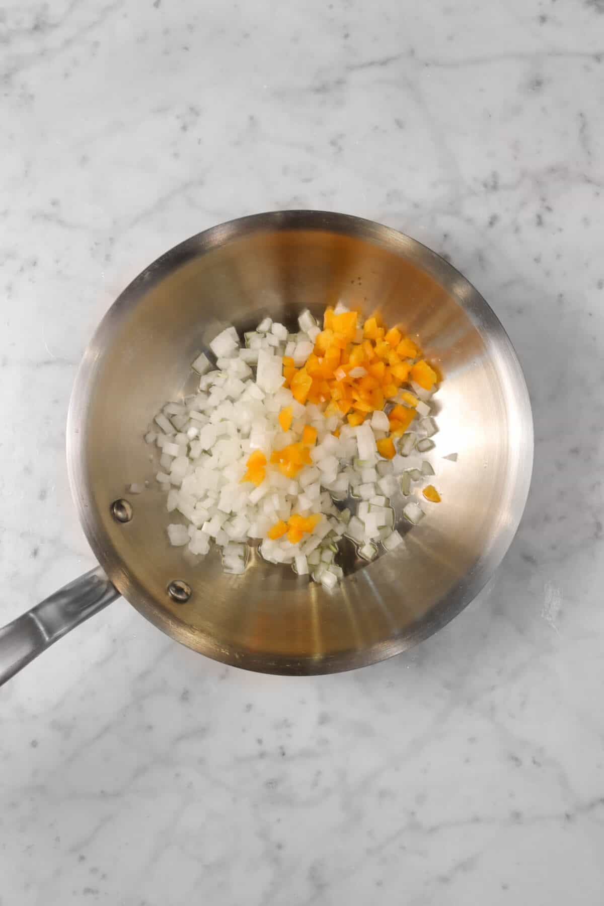 chopped onion and orange bell pepper in a small pan
