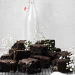 blackout brownies on a wire cooling rack with white flowers, a napkin, and a milk bottle