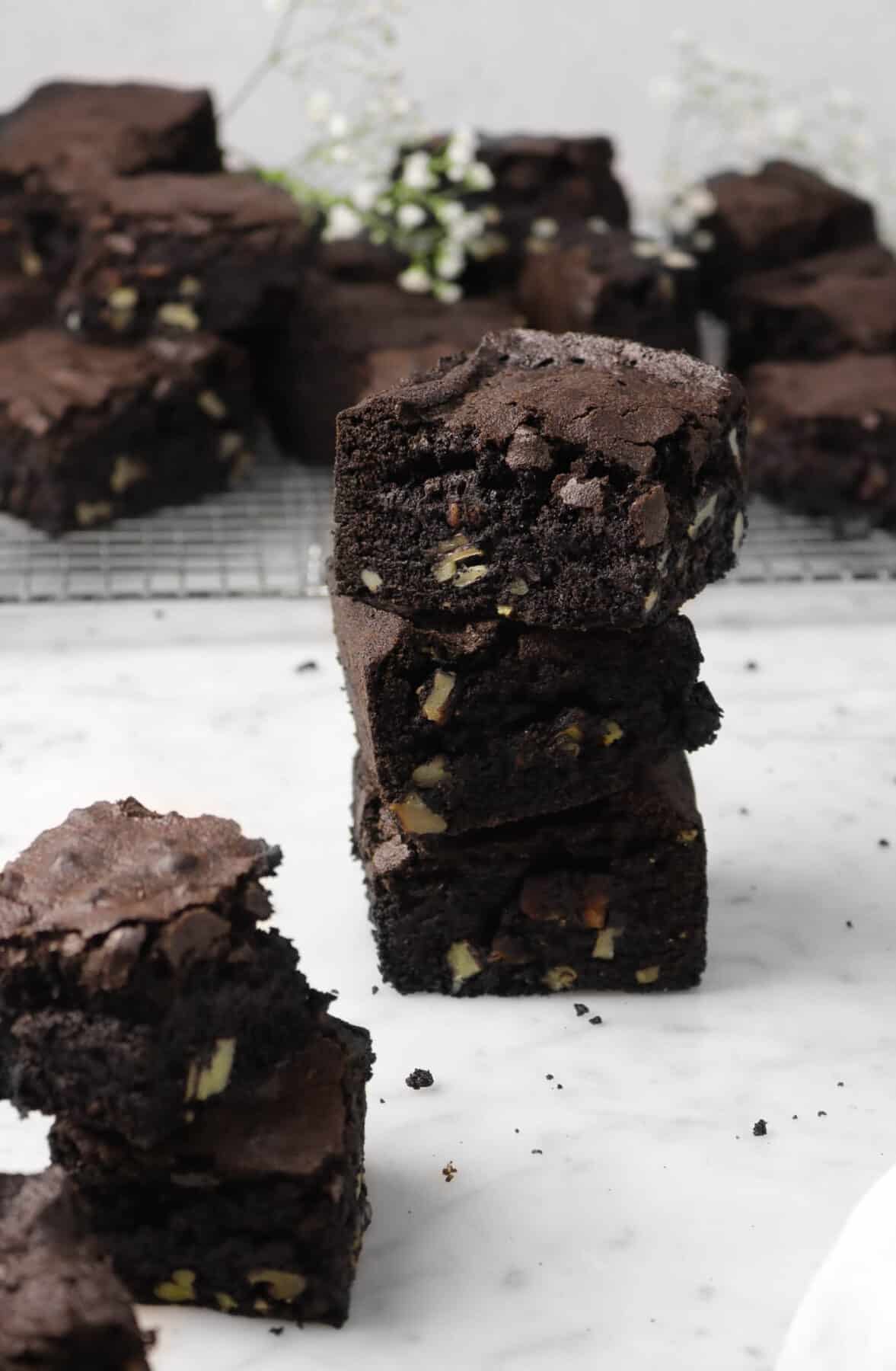three blackout brownies stacked with two more in front and more in the background on a cooling rack