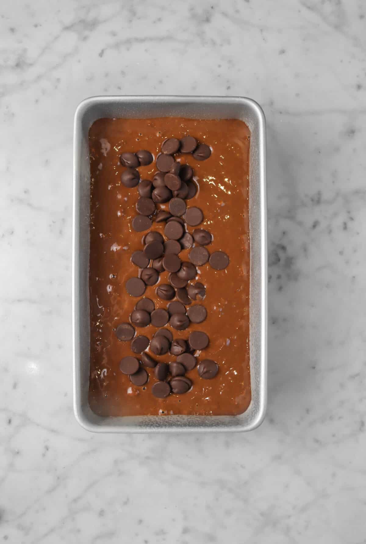 chocolate banana bread batter in a rectangular pan with chocolate chips