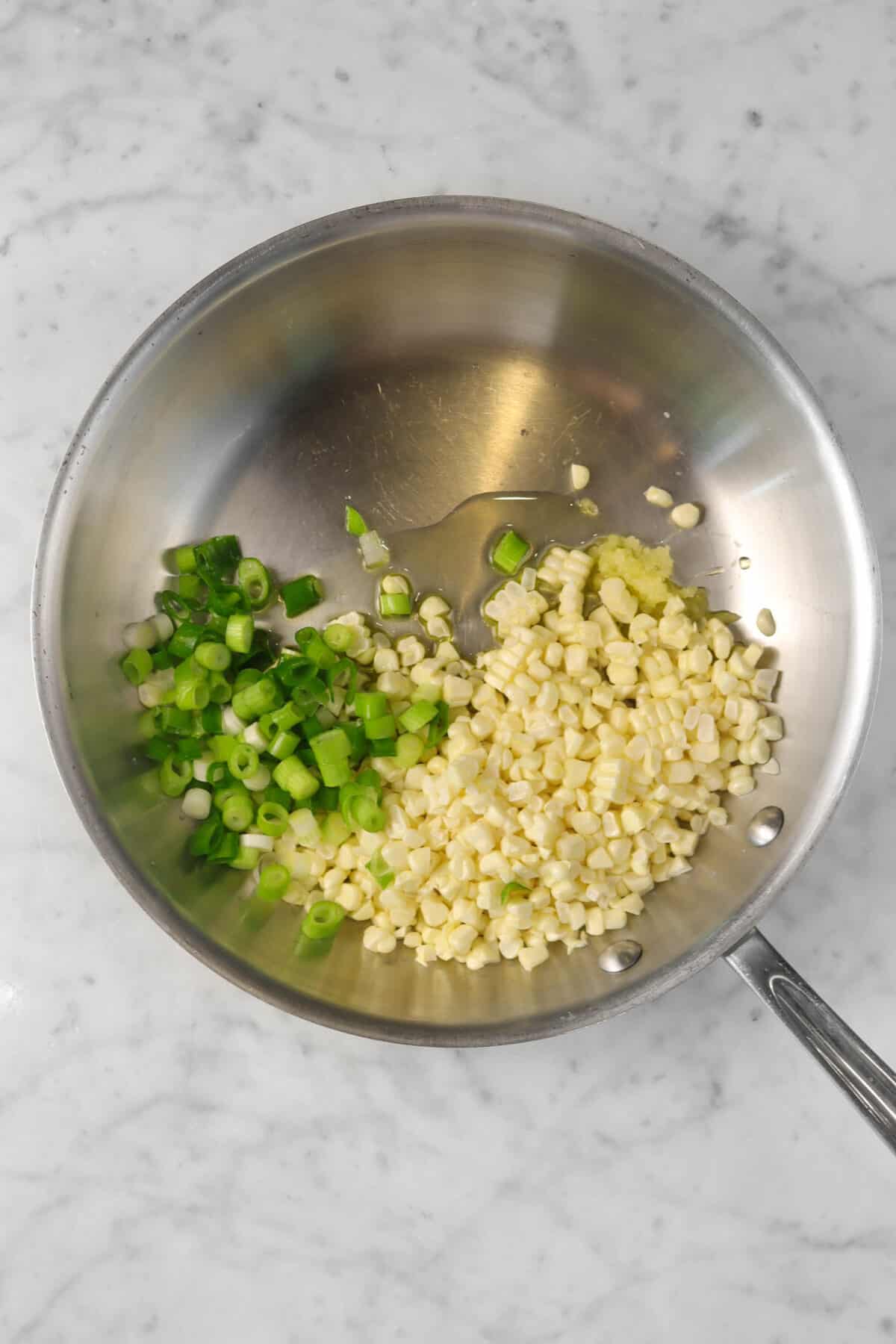 corn, green onions, garlic, and olive oil in a sauté pan
