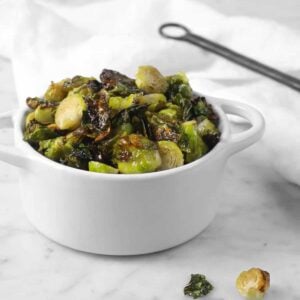 white cocotte with roasted brussel sprouts and a white napkin