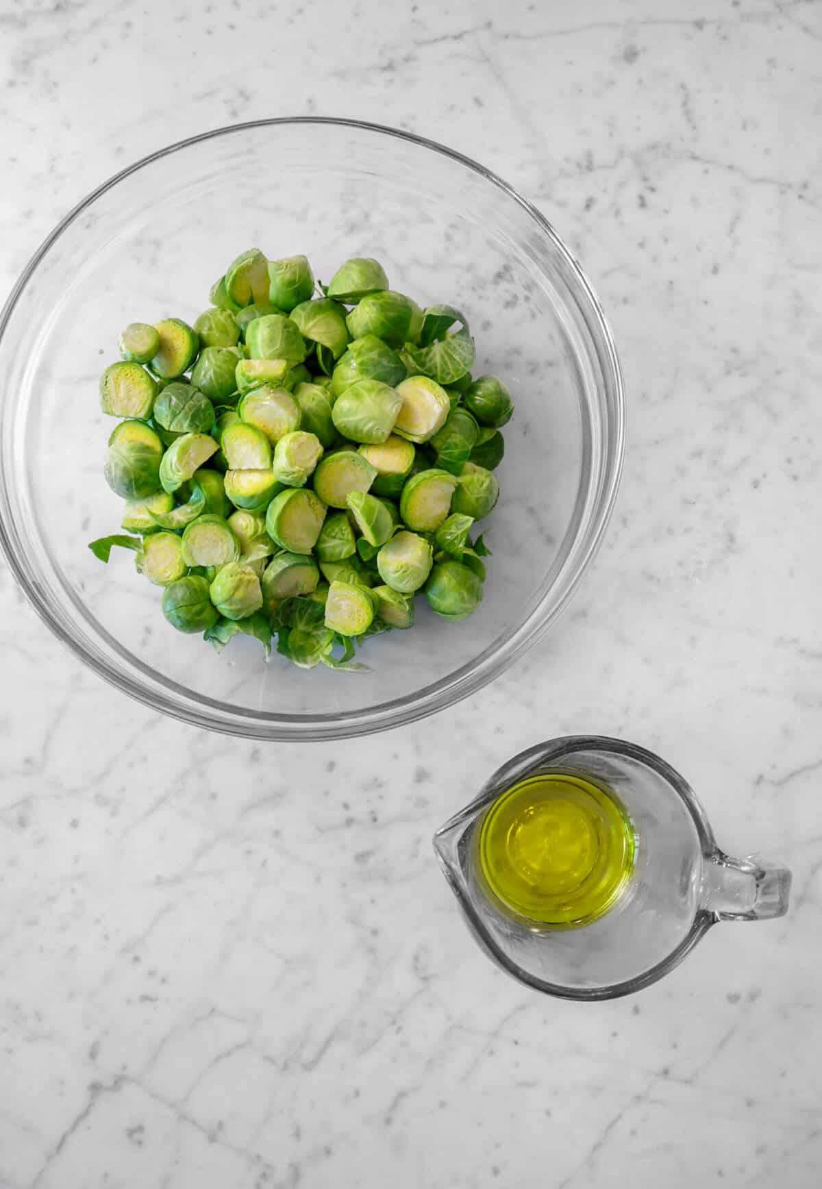 chopped brussel sprouts in a bowl with a measuring cup of oil