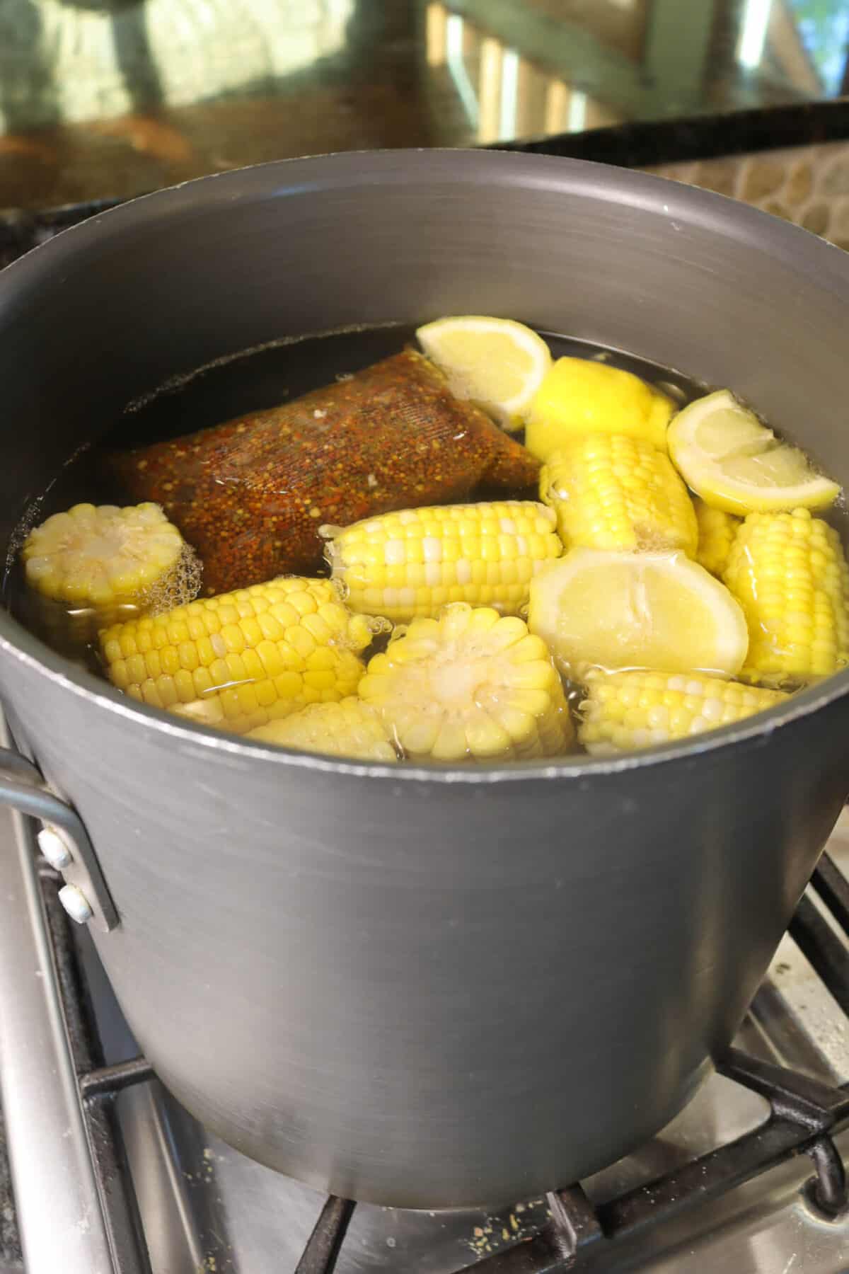 corn, lemons, and a spice packet n a large pot of water