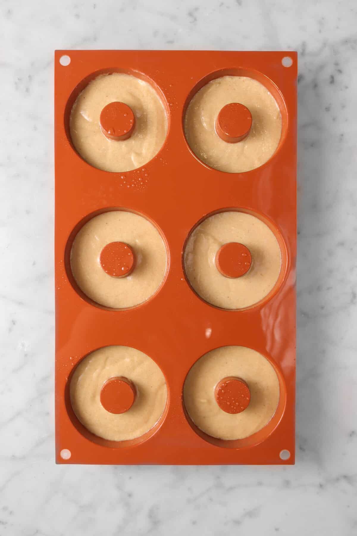 cinnamon donut batter piped into six donut molds