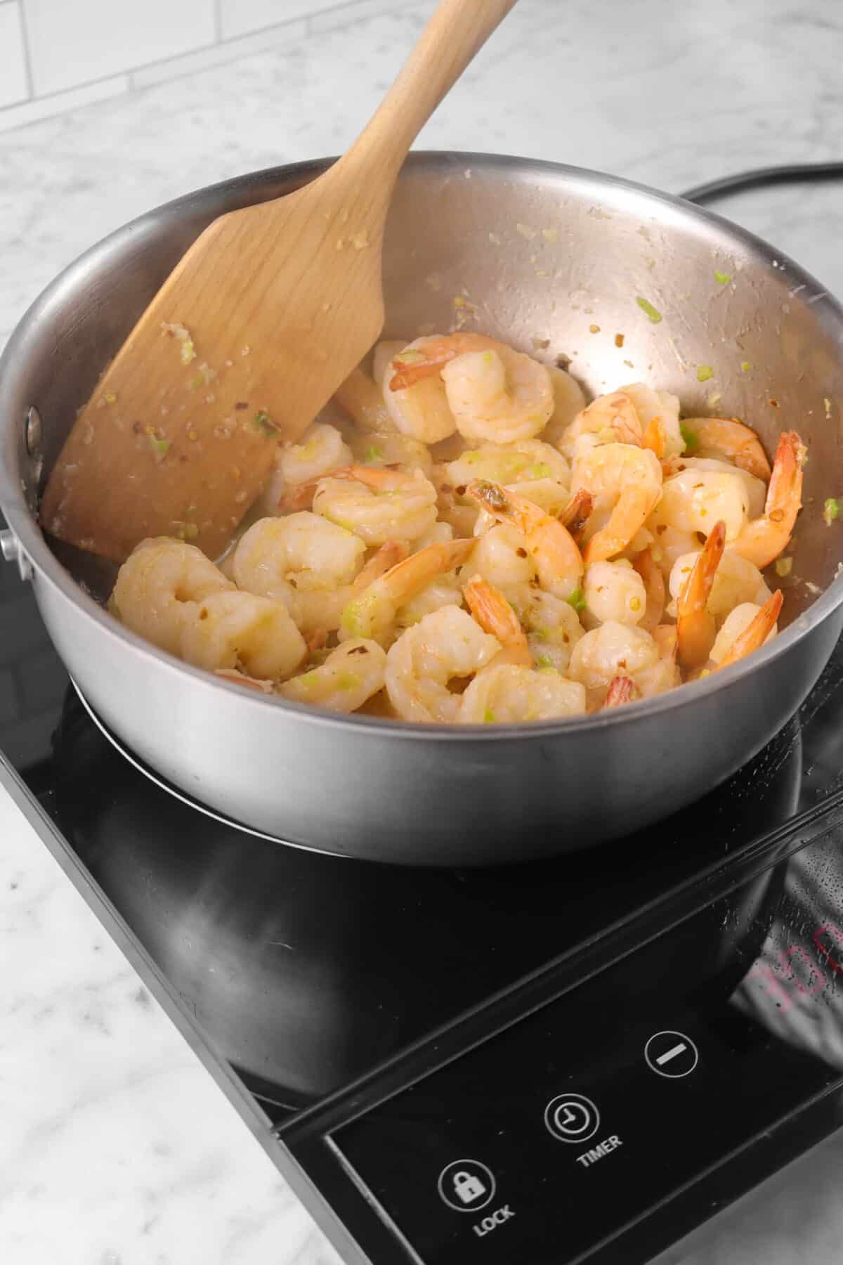 shrimps sautéed in butter mixture with wood spoon