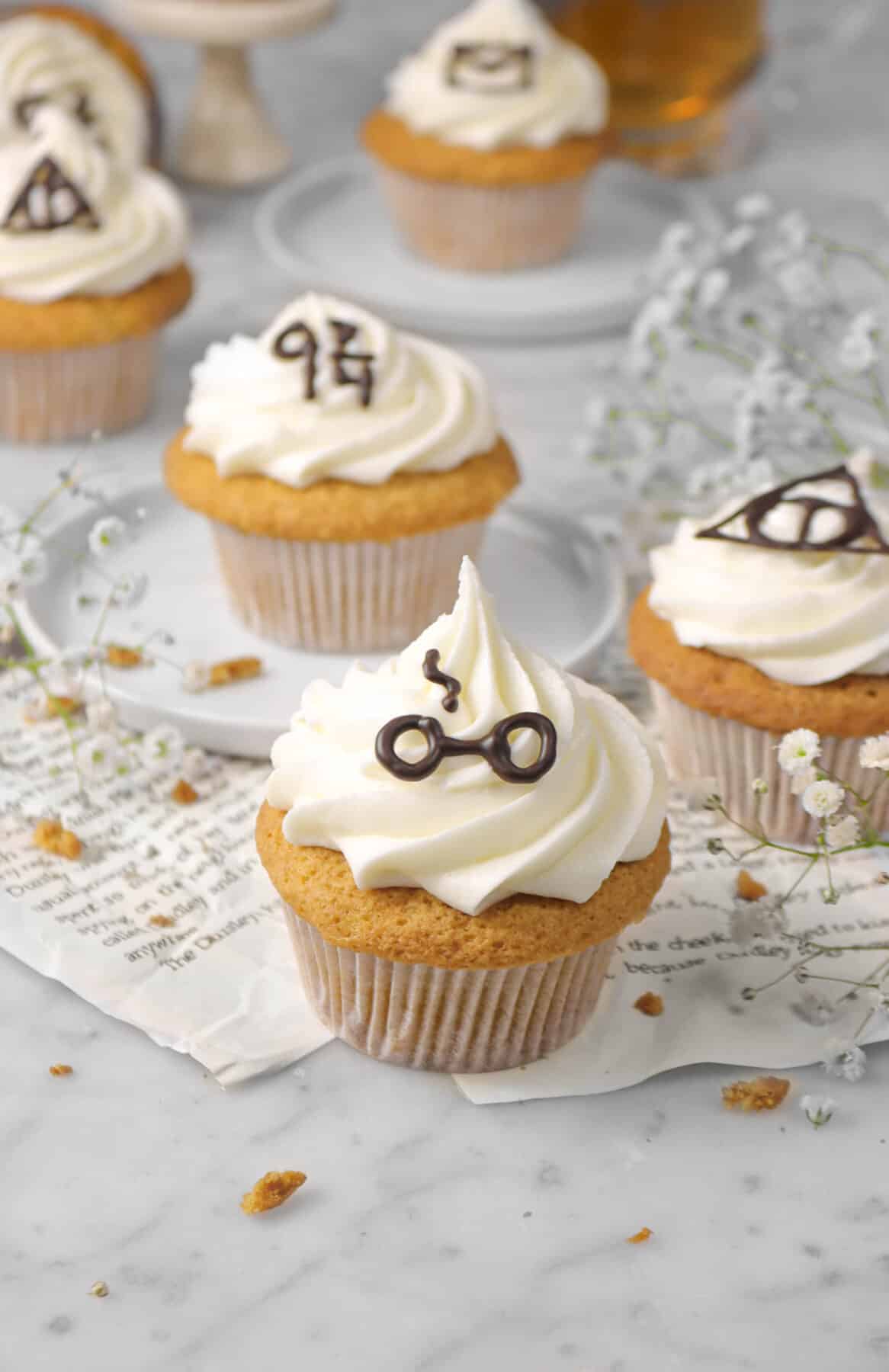 three butterbeer cupcakes with more behind sitting on book pages with flowers