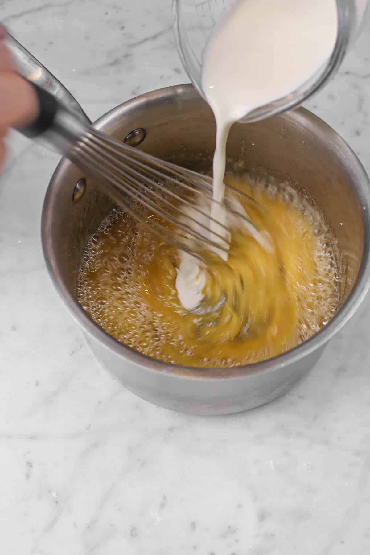 heavy cream being stirred into caramel