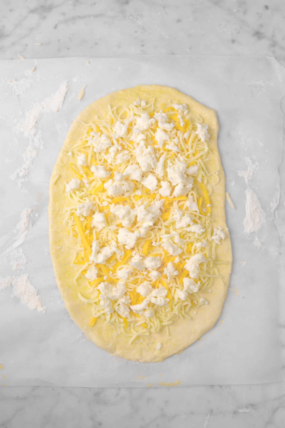 pizza dough rolled out with three cheeses spread over the top