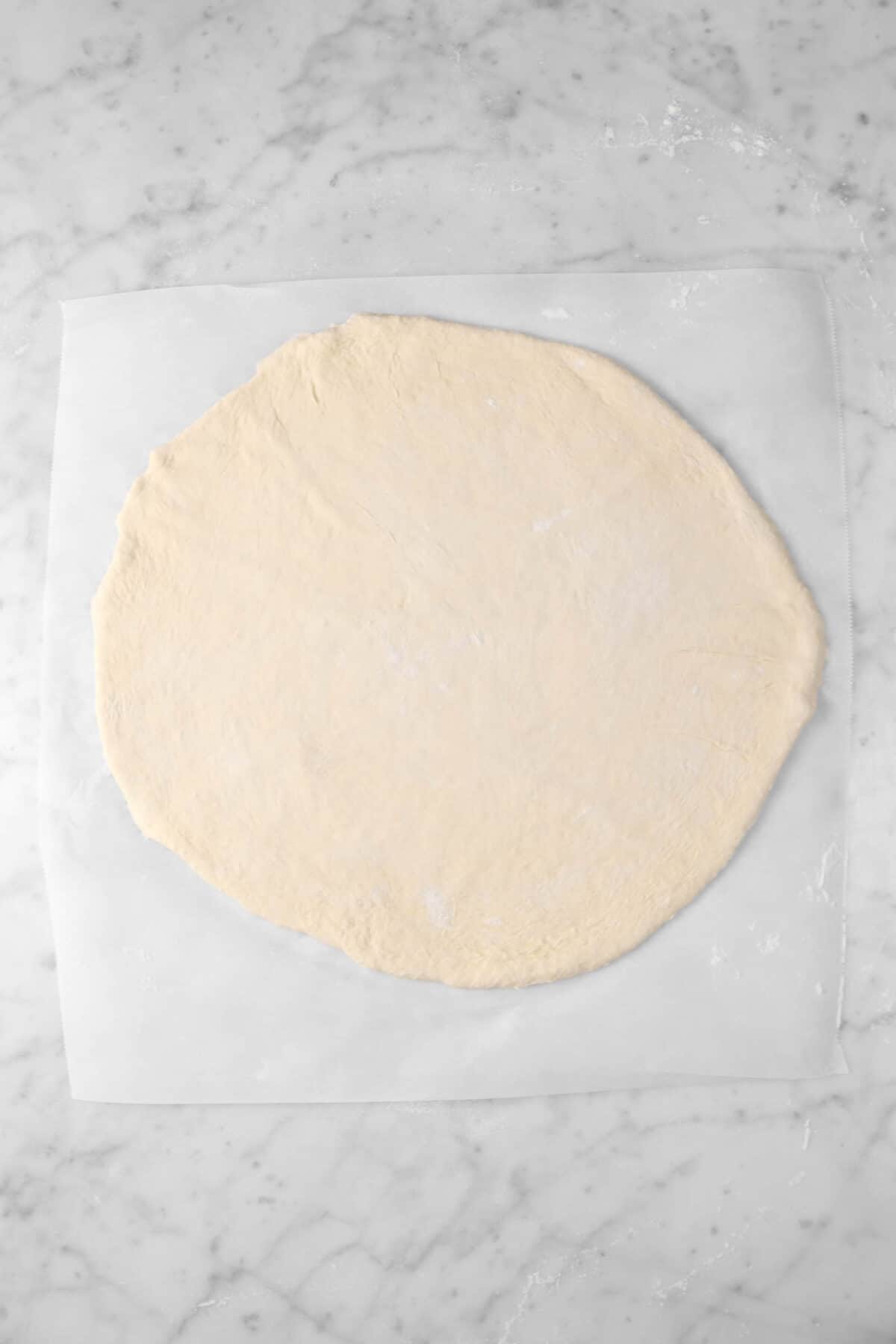 pizza dough rolled out on a piece of parchment