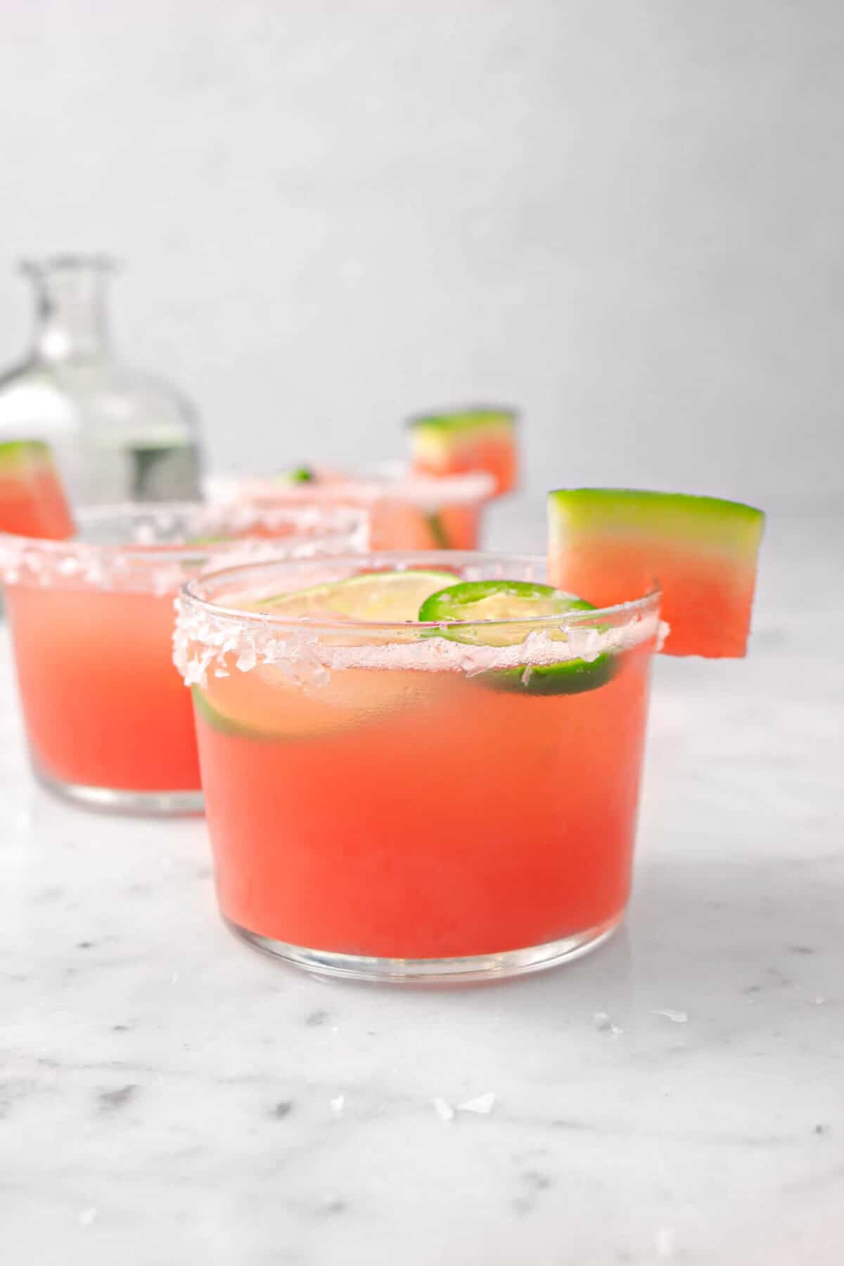 three watermelon jalapeno margaritas on a marble counter