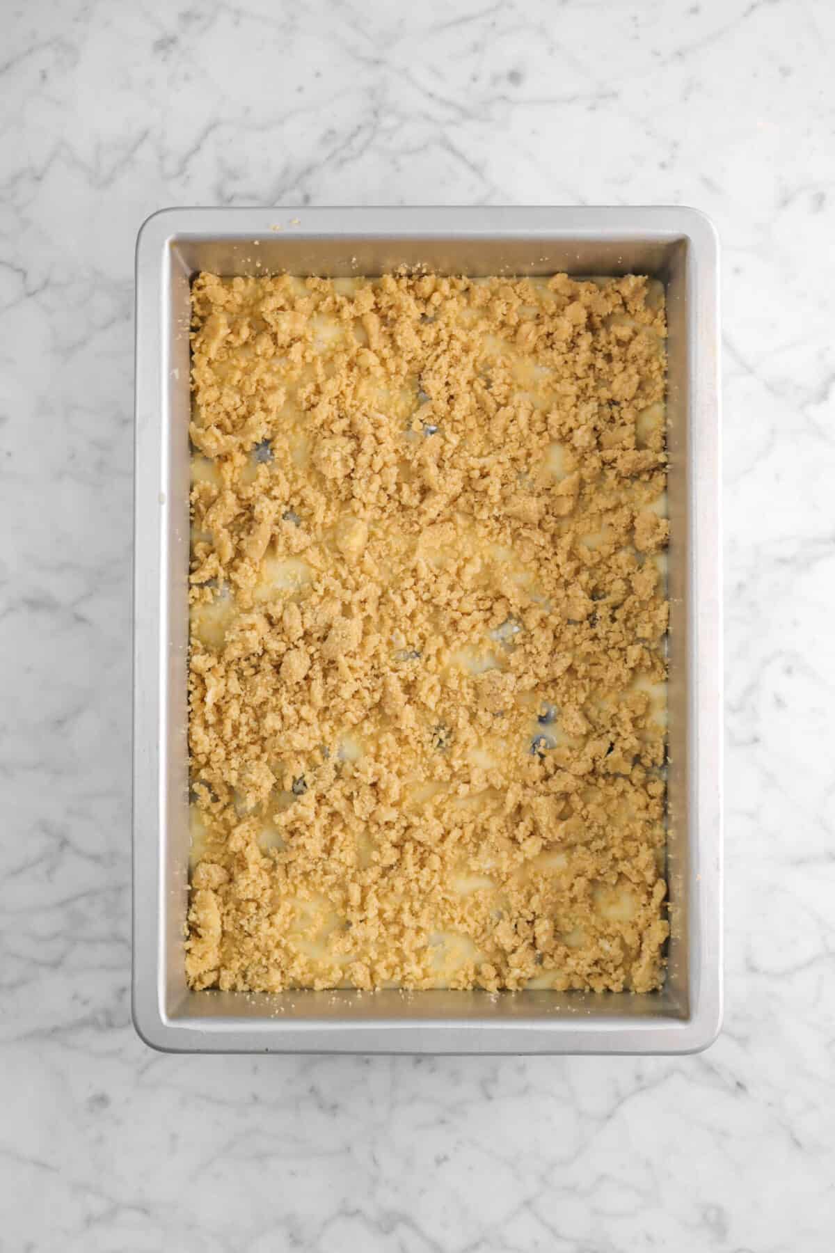 crumble added on top of cake batter in pan