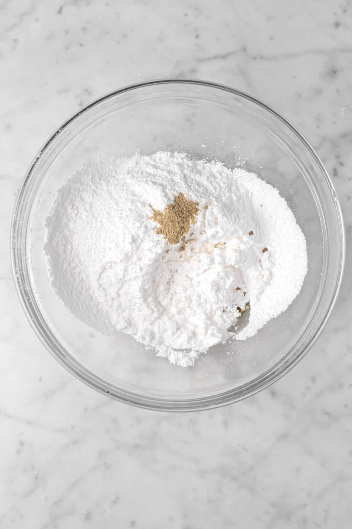 powdered sugar, milk, vanilla, and cardamom in a glass bowl