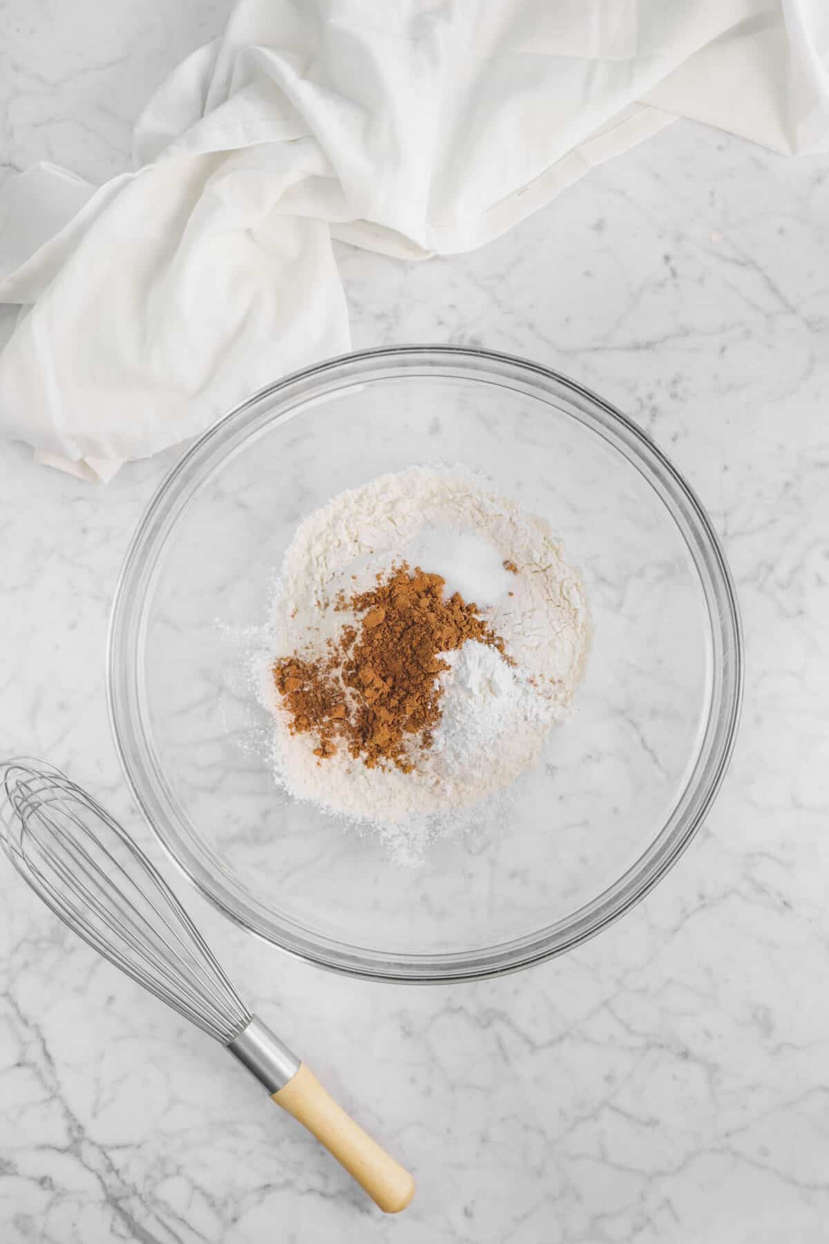 flour, baking powder, salt, and cinnamon in a glass bowl with a whisk