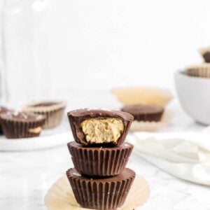 chocolate peanut butter cups stacked on brown paper with more behind