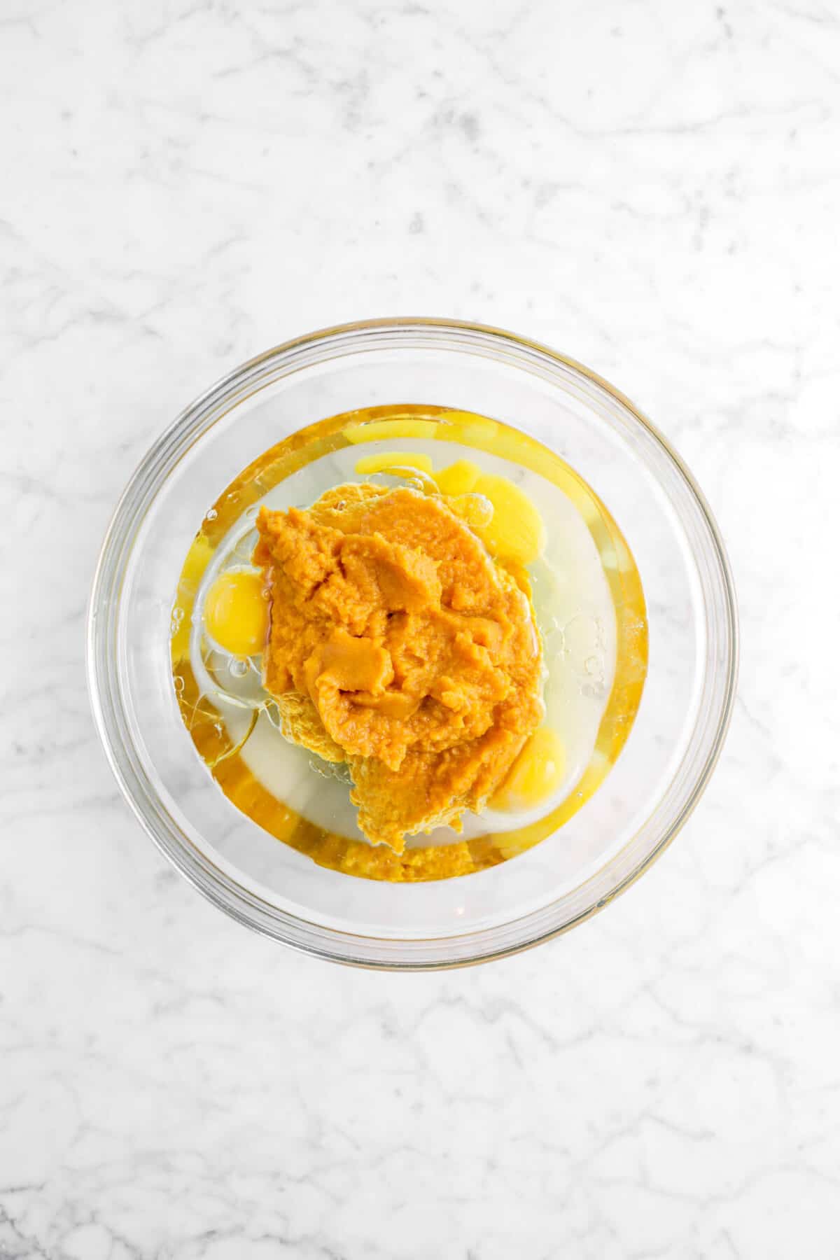 vegetable oil, eggs, and pumpkin in a glass bowl