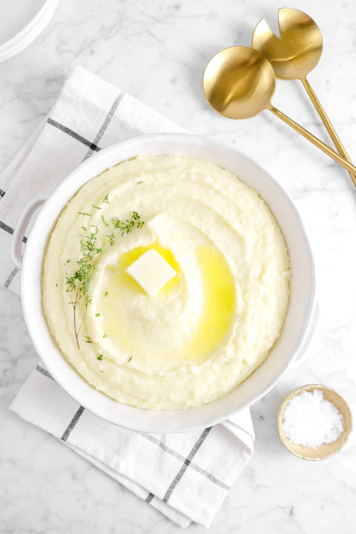 overhead shot of mashed potatoes with a napkin, bowl of salt, and serving spoons