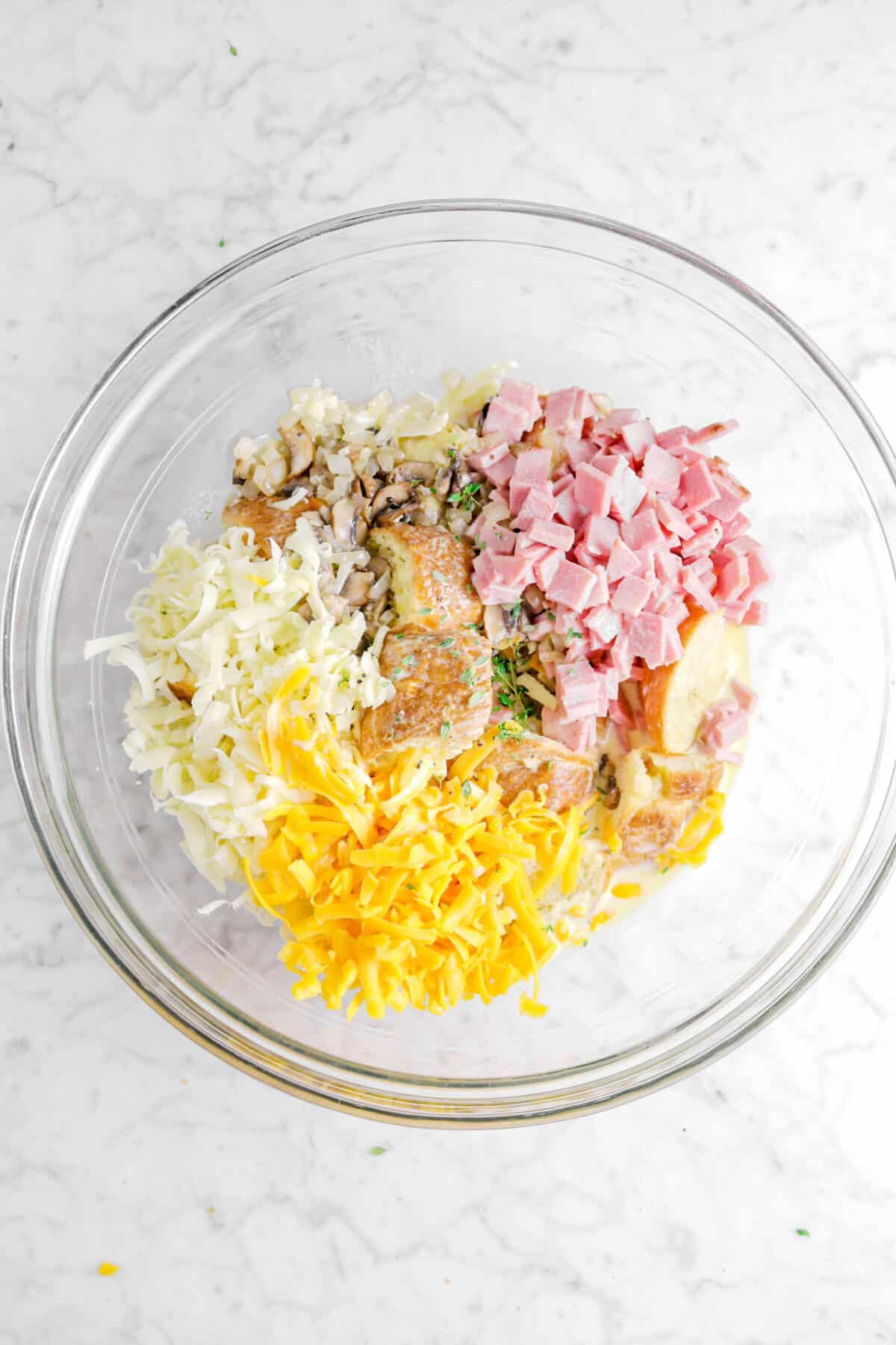 ham, sautéed vegetables, fontina, cheddar, thyme, croissants, and egg mixture in glass bowl