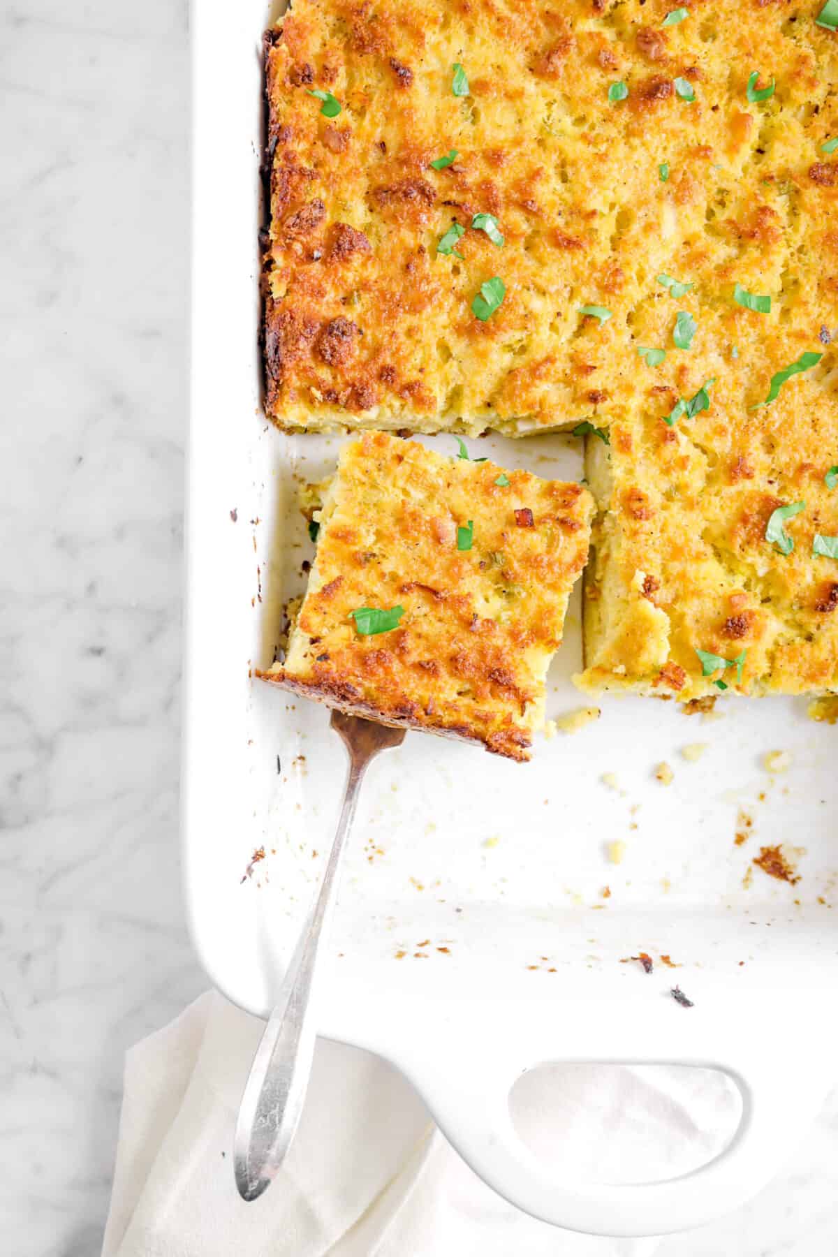 slice of cornbread dressing in casserole dish with serving fork under it