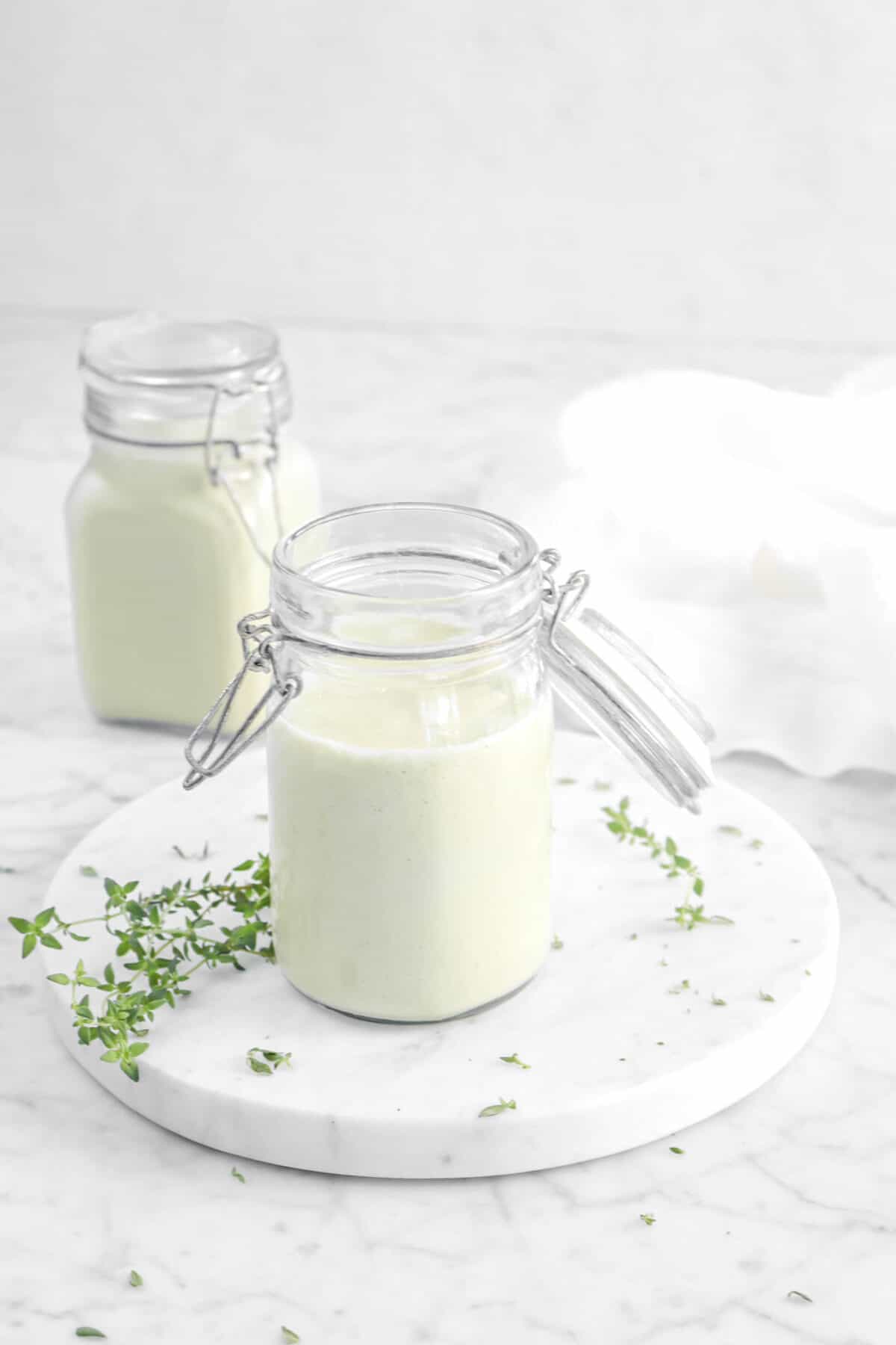 two jars of cream of celery soup on marble board with thyme leaves