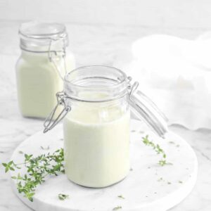 two jars of cream of celery soup on marble board with thyme leaves